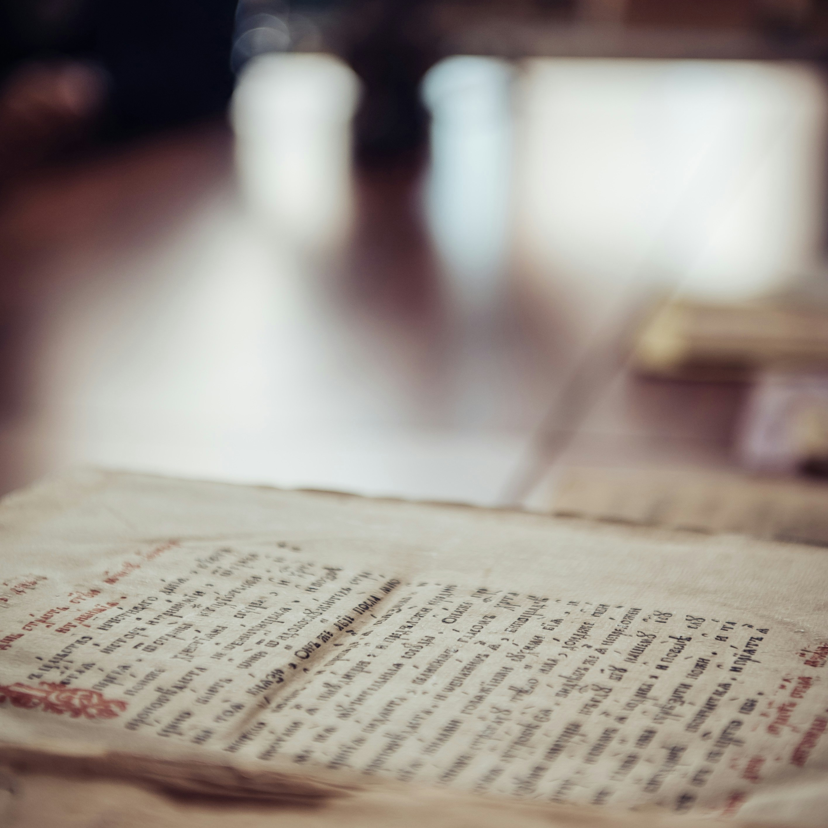 A closeup of an ancient manuscript on the table, with a blurred background and soft lighting
